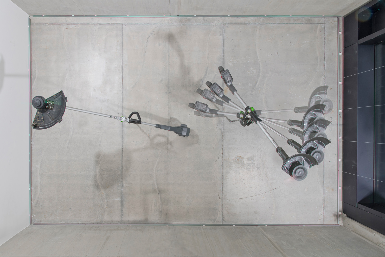 Kunst-Installation von Josephine Riemann: an der Zimmerdecke einer Galerie aufgehängte elektrische Sensen, die in Betrieb sind. Die Schneiden und die Maschinen selbst rotieren.  