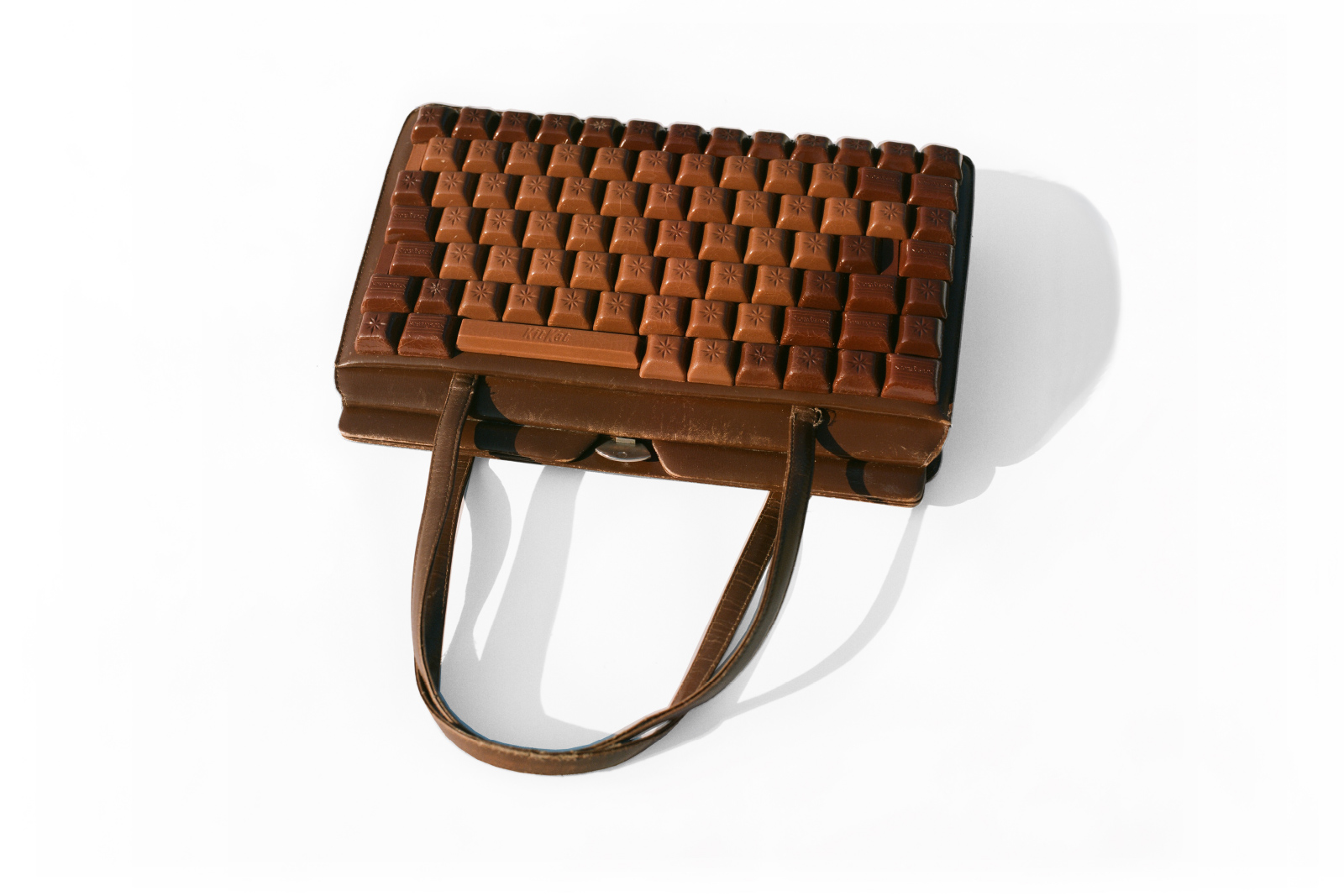 Kunst-Objekt von Josephine Riemann: Das elektronische Gerät ‚Laptop‘ ist hier als braune Damenhandtasche aufgefasst worden. Die Tasten bestehen aus Schokoladestücken.