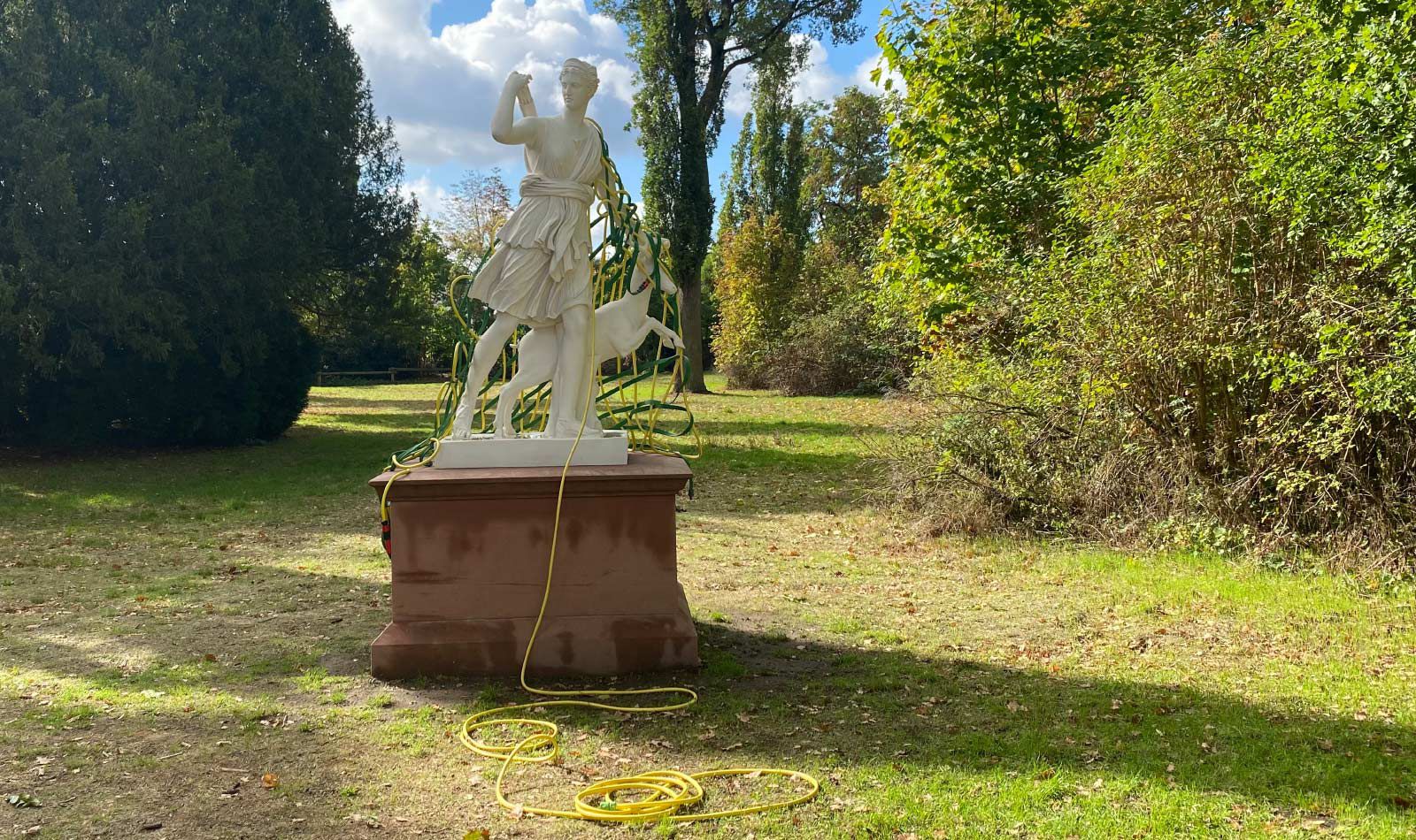Kunst-Installation von Josephine Riemann: ein aus Gartenschlauch gewebtes Netz, welches einer Plastik der Göttin Diana (im Schlosspark Rumpenheim, Offenbach bei Frankfurt am Main) umgelegt wurde.